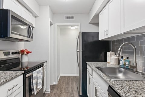 a renovated kitchen with granite counter tops and white cabinets